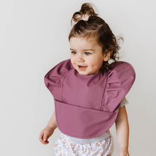 Load image into Gallery viewer, Snuggle Hunny Kids Waterproof Bib in Mauve Frill worn by a toddler with a bow in their hair
