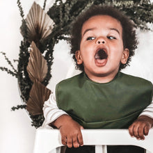 Load image into Gallery viewer, Snuggle Hunny Kids Waterproof Bib in Olive worn by a toddler with their mouth open in a highchair