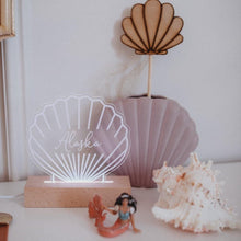 Load image into Gallery viewer, shell shaped personalised night light with the name Alaska engraved onto it shitting next to a shell and a vase