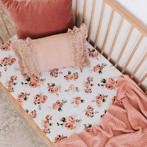 Snuggle Hunny Kids Rosebud Fitted Cot Sheet shown on a cot bed with throw and pillows on top