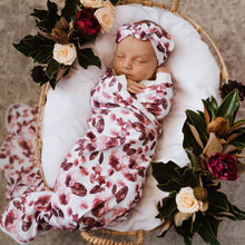 Load image into Gallery viewer, Snuggle Hunny Kids Swaddle and Topknot Set in Fleur design worn by a sleeping baby on bassinet  with flowers on top