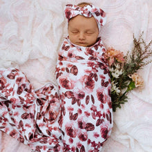 Load image into Gallery viewer, Snuggle Hunny Kids Swaddle and Topknot Set in Fleur design worn by a sleeping baby with flowers next to them