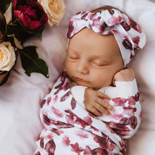 Load image into Gallery viewer, Snuggle Hunny Kids Swaddle and Topknot Set in Fleur design worn by a sleeping baby on bassinet with flowers on top