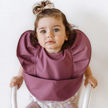 Load image into Gallery viewer, Snuggle Hunny Kids Waterproof Bib in Mauve Frill worn by a toddler with a bow in their hair