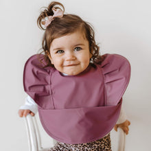 Load image into Gallery viewer, Snuggle Hunny Kids Waterproof Bib in Mauve Frill worn by a toddler with a bow in their hair