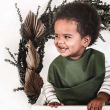 Load image into Gallery viewer, Snuggle Hunny Kids Waterproof Bib in Olive worn by a toddler smiling sitting in a highchair with dried leaves behind