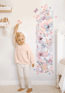 full view of blonde girl standing next to floral fairy garden wall decal height chart 