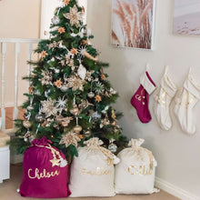 Load image into Gallery viewer, Magenta and ivory santa sacks sitting under a christmas three with three stocking hanging on the wall