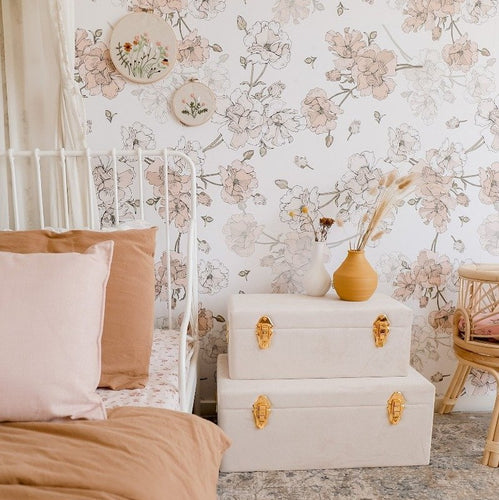girls bedroom with set of two bone storage cases sitting on floor next to bed and vase of flowers ontop