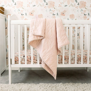 Alimrose cloud soft quilt in petal pink displayed on white cot with flower wallpaper in background