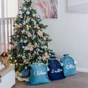 Turquoise blue and navy santa sacks sitting under a christmas tree