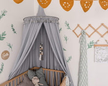 Load image into Gallery viewer, Nursery with grey round canopy over wooden cot and crochet mustard bunting with green leave decals on wall