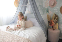 Load image into Gallery viewer, girl sitting on double bed with grey canopy above bed