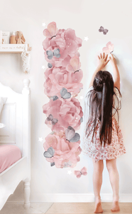 girl standing next to removable wall decal growth hiehgt chart made of pink peonies and purple butterflies