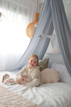 Load image into Gallery viewer, girl sitting on bed with light grey canopy above bed