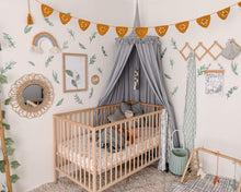 Load image into Gallery viewer, Nursery with grey round canopy over wooden cot and crochet mustard bunting with green leave decals on wall and rattan toys and mirror