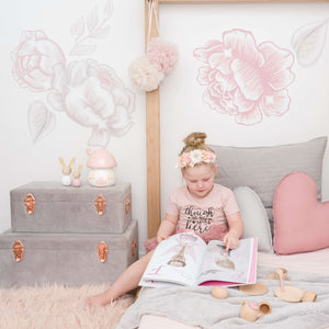 grey storage cases in girls bedroom with girl sitting on bed reading book