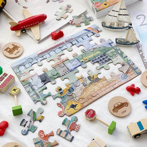 half complete puzzle laying on table with wooden cars, planes, boats and toys around the puzzle