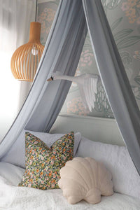 light grey canopy hanging in girls bedroom with cushions on bed