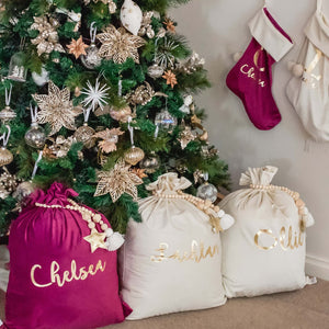 purple and ivory santa sacks sitting under a christmas tree with gold decorations