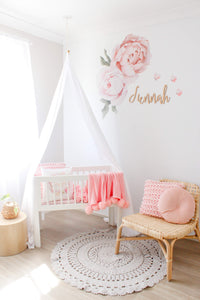 white drape canopy in girls nursery drapped over white bassinet with pink details and decorations