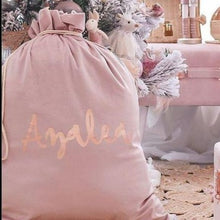 Load image into Gallery viewer, Blush pink santa sacks personalised with the name Azalea in rose gold font sitting in a girls bedroom