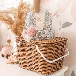 silver sequin bunny crown sitting on top of brown cane basket in child's bedroom