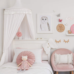 White round canopy sitting over white timber bed with dusty pink velvet cushion on bed and velvet armchair in a girls room