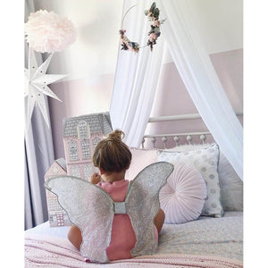 white drape canopy hanging above single bed with girls sitting on bed wearing silver angel wings