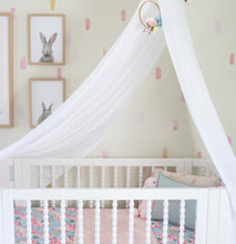 Load image into Gallery viewer, white drape canopy hanging above white cot with bed and pink bedding and pictures of rabbits on the wall