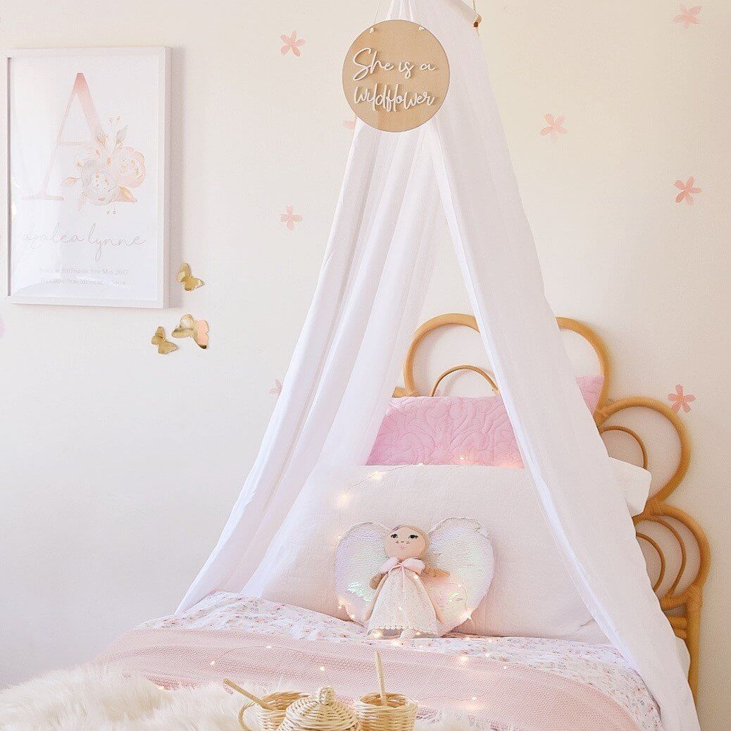 white drape canopy hanging above simngle bed in girls toddler bedroom with doll sitting on bed